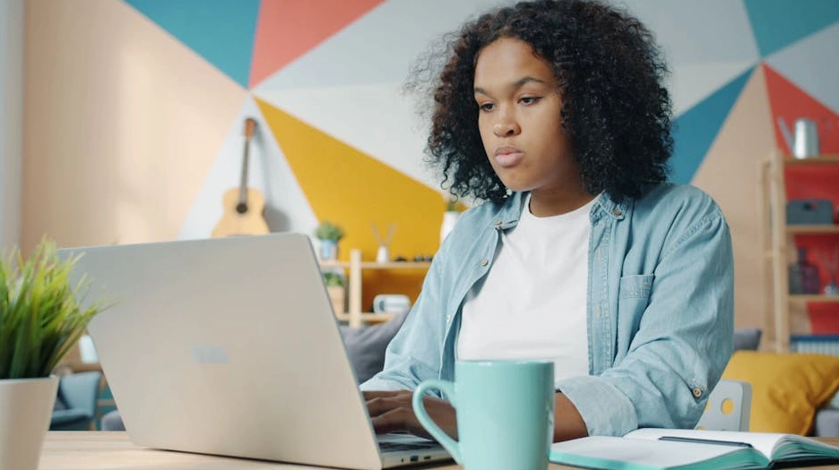 Usměvavý student s notebookem v moderní kavárně.